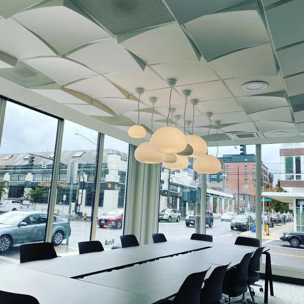 Custom decorative pendant light fixture installation in a modern commercial conference room with architectural ceiling elements