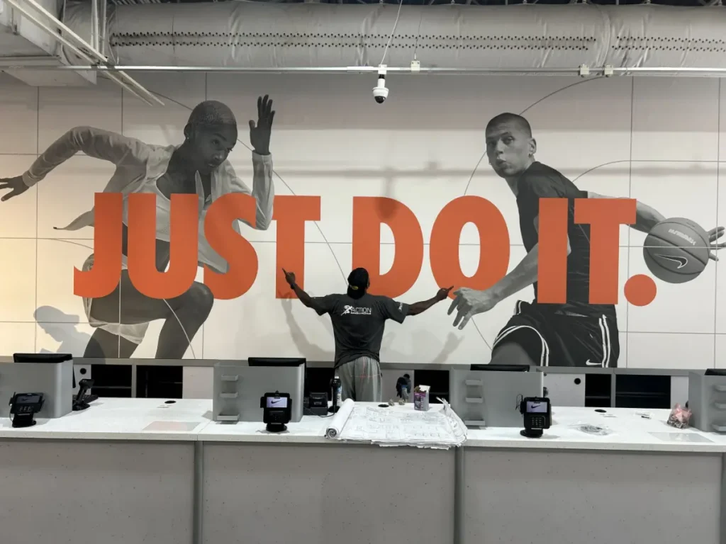 Large-format retail wall graphic installation featuring Nike branding and motivational "Just Do It" display